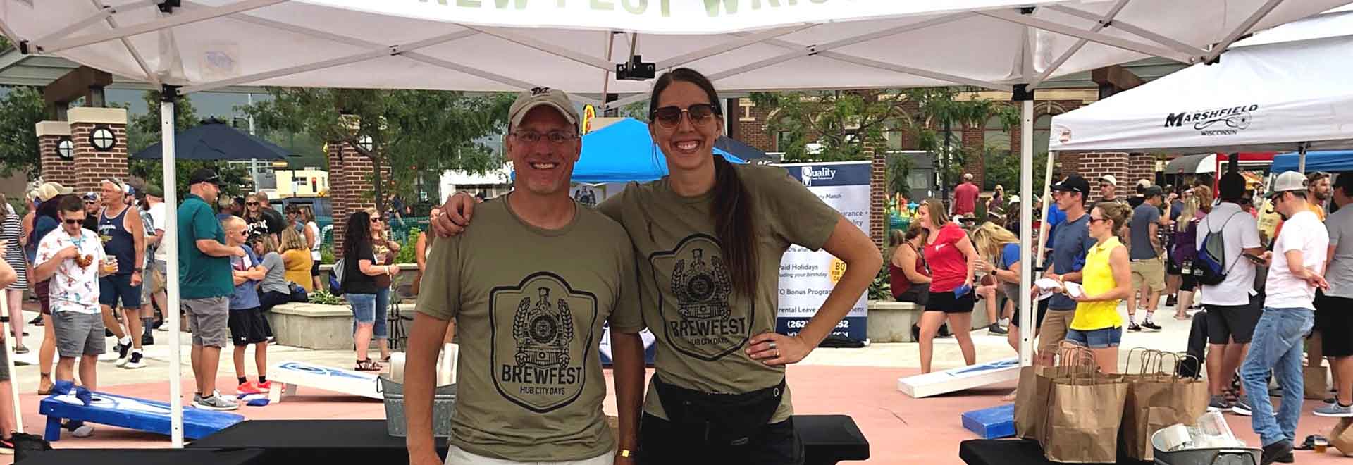 Two volunteers under a tent at an outdoor event